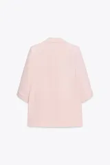 Blazer color marrón oscuro, de corte recto, con cuello solapa y hombreras. Tiene mangas 3/4 con trabilla y botón dorado, y bolsillos delanteros con solapa.