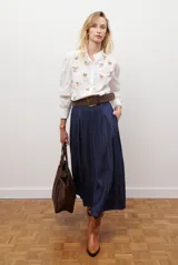 Falda larga de jean azul oscuro, corte acampanado con paneles y costuras visibles.