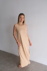 Vestido largo azul marino de tejido acanalado, con escote redondo y mangas cortas tipo hombrera. Presenta una abertura lateral en la falda.