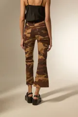 Pantalón de jean estampado camuflado en tonos marrones y beige, de corte flare, calce alto y ruedo deshilachado.
