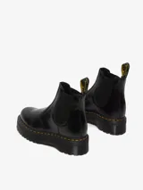 Botas Chelsea Dr. Martens modelo 2976 Quad, de cuero negro pulido, con elásticos laterales, plataforma de 4 cm y costuras amarillas.