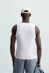 Musculosa blanca de algodón con cuello redondo y sisas amplias, corte ajustado.