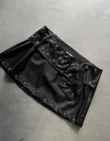 Minifalda negra de cuerina con cinturón con hebillas metálicas.