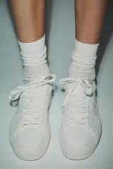 Zapatillas deportivas blancas con detalle de pespuntes en el cuerpo y suela de plataforma.
