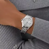 Reloj analógico Guess modelo Mist, con caja y pulsera de eslabones de acero inoxidable color plateado. La esfera plateada presenta índices aplicados y pequeños cristales en las posiciones de las 12, 3, 6 y 9 horas.