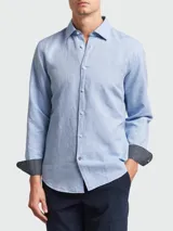 Camisa de manga larga para hombre, color celeste claro, con cuello clásico y botones frontales. El interior del puño presenta un estampado geométrico en contraste en color negro y blanco.