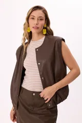 Chaleco marrón de símil cuero suave con botones a presión y ruedo regulable.