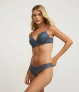 Bombacha de lencería color azul grisáceo, modelo bikini hilo, confeccionada en encaje floral con detalles de costura en forma de 'V' en el frente.