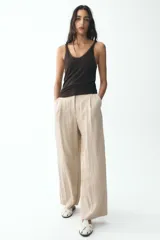 Pantalón negro de tiro alto con bolsillos delanteros, pinzas y corte ancho.