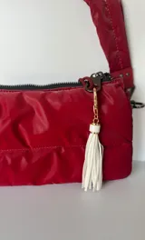 Llavero con gancho dorado y flecos de cuero sintético color rosa pálido.