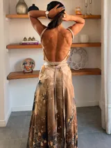 Vestido largo de tela fluida, color verde esmeralda con estampado abstracto en tonos turquesa y detalles dorados. Diseño asimétrico con un solo tirante tejido en el hombro.