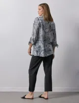 Camisa de mujer estampada con hojas en blanco y negro, cuello con solapa, abertura central con botones, bolsillos aplicados en el delantero y mangas largas con lazo.