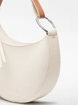 Bolso de hombro tipo baguette color crema, con textura granulada y asa corta regulable.