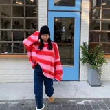 Sweater de punto grueso a rayas horizontales rosas y rojas, de corte holgado y cuello redondo.