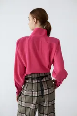 Camisa de cupro color fucsia, con cuello alto, abotonado frontal y terminación redondeada.