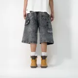 Bermuda de jean negra con efecto lavado, corte holgado, bolsillos traseros y laterales, y detalle de logo bordado en blanco.