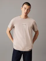Remera color beige claro de corte recto, cuello redondo y mangas cortas. Estampado frontal con el logo de Calvin Klein Jeans en color blanco.