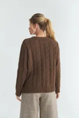 Cardigan marrón de tejido de punto industrial con ochos cruzados, escote en V y bolsillos delanteros. Tejido en 100% lana fina sin teñir.