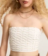 Blusa cropped sin breteles color blanco con pequeños apliques dorados.