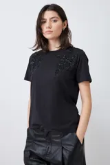 Remera negra de manga corta con apliques bordados en el escote.