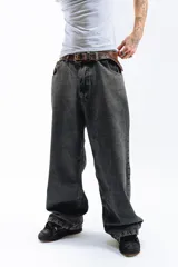 Pantalón de jean azul desgastado, corte mega baggy, con bordado dorado en el bolsillo trasero y botones personalizados.