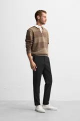 Pantalón negro de corte slim fit, confeccionado en tejido elástico. Cuenta con cintura elástica, bolsillos frontales y traseros de vivo. Cierre frontal con cremallera y botón.