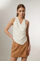 Top blanco de poliéster, al cuerpo y con cuello drapeado.