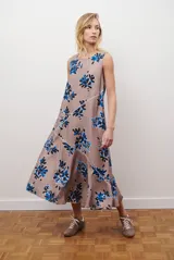 Vestido midi color beige con estampado de hojas en tonos violeta, verde y negro. Diseño sin mangas, con escote redondo y falda acampanada.