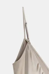 Vestido midi de satén color gris topo, con escote en V y tirantes finos regulables. El ruedo es asimétrico y está adornado con encaje. Cierre lateral con cremallera oculta.