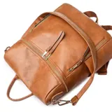Mochila marrón de eco cuero con cierre superior y bolsillos frontales con cierre.