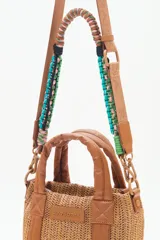 Cartera tote mini color negro, confeccionada en tejido tipo rafia. Cuenta con bolsillos internos, dos correas desmontables y abertura superior con cierre.
