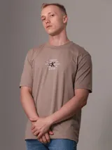 Remera color beige con cuello redondo y mangas cortas. Estampado frontal con diseño de sello de la ciudad de Nueva York y monograma bordado.