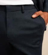 Pantalón de traje de corte super slim, color azul oscuro, confeccionado en tejido de poliviscosa con textura discreta. Presenta trabillas en la cintura, cierre de cremallera y botón, y bolsillos laterales y traseros.
