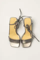 Sandalias plateadas de cuero con tacón bloque, plataforma delantera y tiras finas para atar al tobillo.