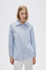 Camisa celeste a rayas verticales blancas, de corte recto, manga larga, cuello camisero y bolsillo en el pecho.