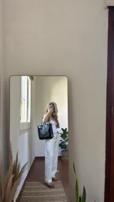 Bolso tote negro con textura símil cuero de cocodrilo, bolsillo externo color beige y asas marrones.