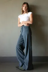Pantalón de jean azul oscuro de pierna ancha con detalle de trenzado en bolsillos y cinturón.