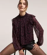 Blusa de chiffon negra con estampado floral liberty en tonos rosados, cuello alto con lastex y volados en los hombros. Mangas largas con puños ajustados.