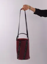 Bolso matero color bordó, de cuero, con doble asa (una de mano y otra larga desmontable), divisor interno para termo y mate, y bolsillo interior.