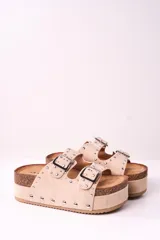 Sandalias beige con plataforma de corcho y doble tira con hebillas y tachas plateadas.