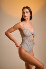 Malla entera con estampado geométrico en tonos beige y marrón, con breteles finos y abertura en el abdomen.