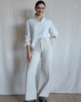 Pantalón de jean de tiro alto, color beige claro, con corte acampanado y costuras verticales al frente.