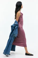 Vestido midi sin mangas color rosa viejo, de punto elástico con leve brillo, corte ajustado y frunces en escote, hombros y en un lateral de la cintura para crear un efecto drapeado.