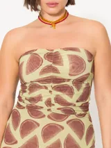 Vestido strapless confeccionado en mesh estampado con motivos geométricos color marrón sobre fondo verde lima. Lleva frunces en el delantero y cierre metálico niquelado en la espalda. Su largo llega por debajo de la rodilla.