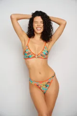 Corpiño de bikini triangular con estampado abstracto en tonos rosados y verdes, con aro metálico en el centro y breteles finos negros.