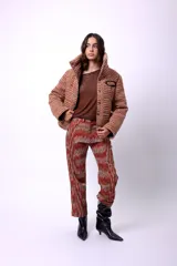 Campera corta con estampado abstracto en tonos marrones y beige, cuello alto, cierre frontal con botones a presión, bolsillos delanteros y bordado negro con las iniciales CP. Forro interior y relleno liviano de guata.