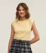 Blusa sin mangas color amarillo pálido, con cuello redondo y pliegues delanteros.