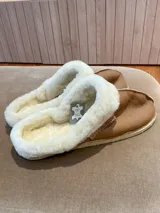Pantuflas marrones de cuero lanar con interior de piel sintética blanca y suela de goma.