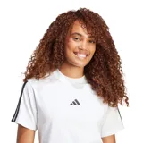 Remera blanca de mujer Adidas Essentials, con cuello redondo, manga corta y las tres tiras características de la marca en color negro sobre los hombros y mangas. El logo de Adidas está estampado en el pecho.