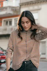 Polera de punto a rayas horizontales color celeste y blanco, de cuello alto y mangas largas.